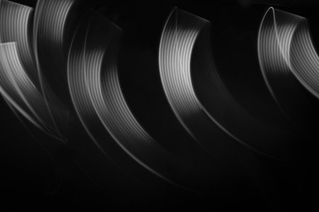 White neon flowing wave of light as trails with smooth stripes on black background, pattern. Abstract background with motion light effect, light painting in disco style.の写真素材