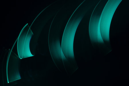 Turquoise green glow neon wave of light with smooth stripes on black background, striped pattern. Abstract background with flowing line in motion, light painting in vapor wave style.の写真素材