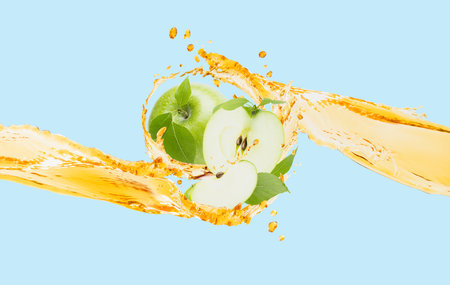 Juicy flow of yellow apple juice and green apples, green leaves, splashes levitated, blue background. Healthy refreshing fruits, drink for advertising, label product, flyer, poster, card.の写真素材
