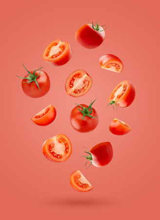 Fresh red cherry tomatoes with green stem whole, sliced fall as flow in art composition on pink...