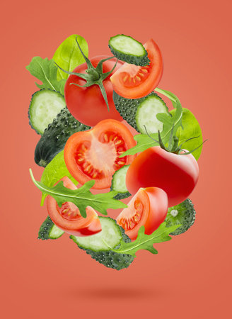 Vegetable salad ingredients - red tomatoes, green cucumbers, green leaves - fly as art swirl composition on pink background. Summer healthy food vegetables for detox menu, fitness meal, advertising.の写真素材