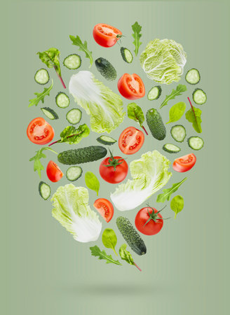 Fresh summer vegetable salad background. Salad ingredients - chinese cabbage, tomatoes, cucumber, leafy greens fly as flow on green background. Great for farm-fresh produce, culinary advertising.の写真素材