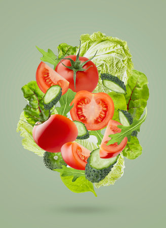 Fresh summer vegetable salad background. Salad ingredients - chinese cabbage, tomatoes, cucumber, leafy greens fly as swirl on green background. Great for farm-fresh produce, culinary advertising.の写真素材