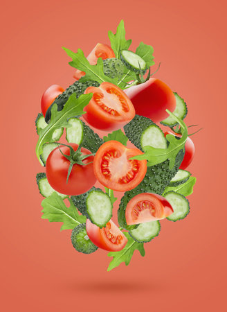 Organic vegetable salad ingredients - red tomatoes, green cucumbers, mixed greens, levitation as flow in art composition on pink background. Vegetarian diet food for detox cooking, fitness diet.の写真素材