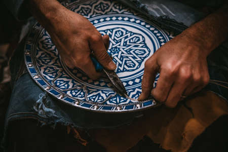 the man works doing crafts on a plate in moroccoの写真素材