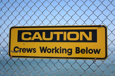 Caution crews working below sign on bridgeの写真素材