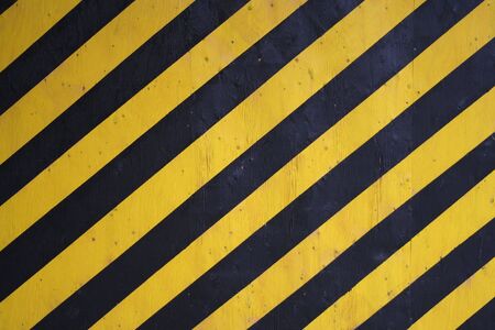 Black and yellow diagonal warning stripes backgroundの写真素材