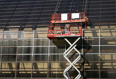 workers on mechanical lift repairing office windows