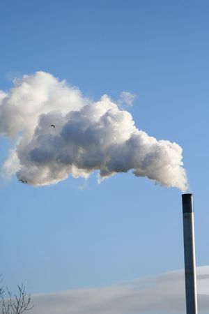 chimney billowing white smoke into blue skyの写真素材