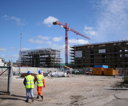 construction workers walking near building site with crane