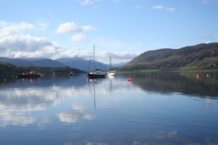 assorted boats on Loch Broom with blue sky from Ullapool Scotland