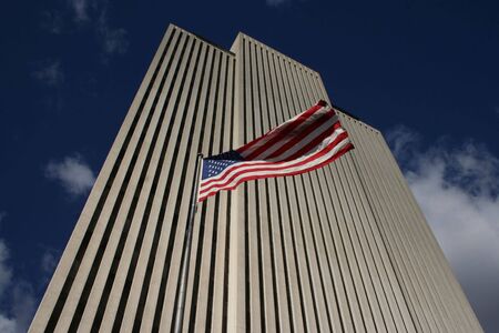 Looking up at white skyscraper with American Flag