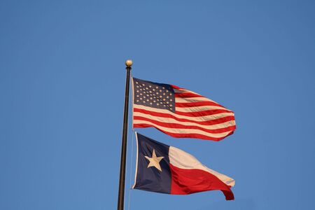 American and Texan flags on pole at duskの写真素材