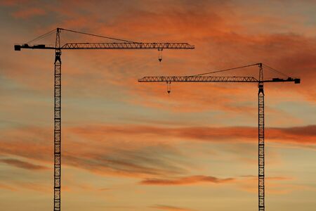 Construction cranes at sunset with colourful cloudsの写真素材
