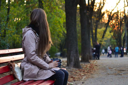 Girl sitting on the bench in park in the eveningの写真素材