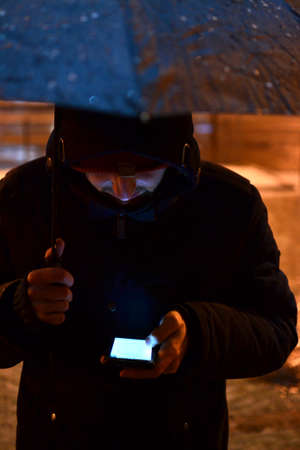 Man with cell phone under umbrellaの写真素材