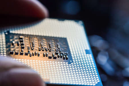 Computer CPU processor micro chip between fingers close upの写真素材