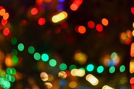 Christmas lights background. Blurred electric garland on Christmas tree. Red, green, yellow, orange,...