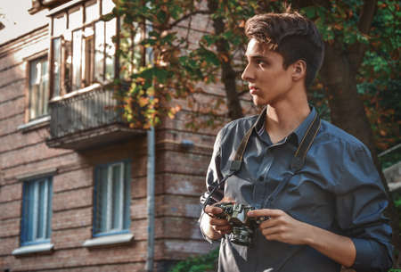 Hipster teenager boy photographer with retro film photo camera