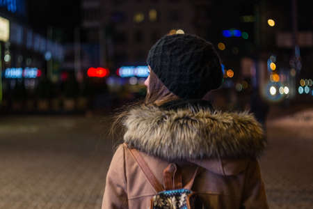 Lonely girl walking through night city streetの写真素材