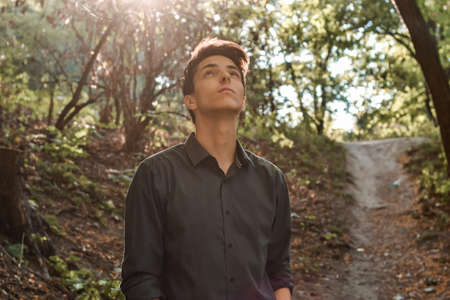 Pensive faithful teenage boy looking up hopingの写真素材