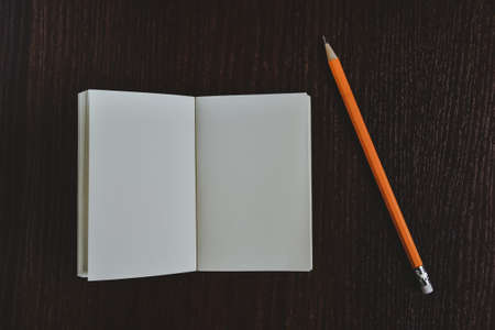 Open diary pocket book and pencil on black backgroundの写真素材