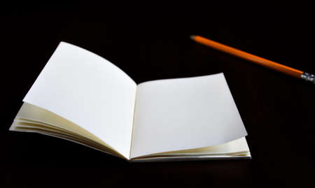 Open diary pocket book and pencil on black background