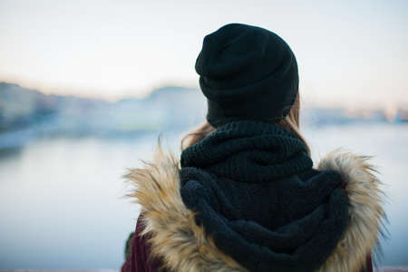 Back view of a sad hipster girl against blurred winter backgroundの写真素材