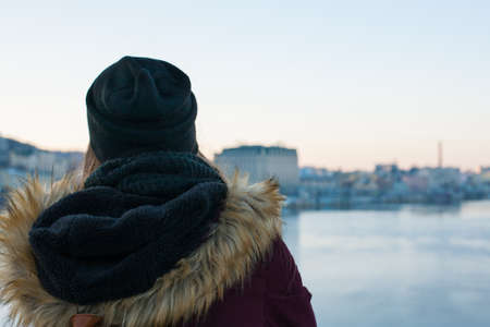 Girl traveler standing on the bridge enjoying view of the city across the riverの写真素材