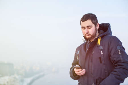 Man traveler using cellphone against winter cityscapeの写真素材