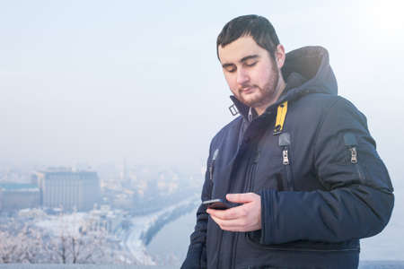 Man traveler using phone against winter cityscape