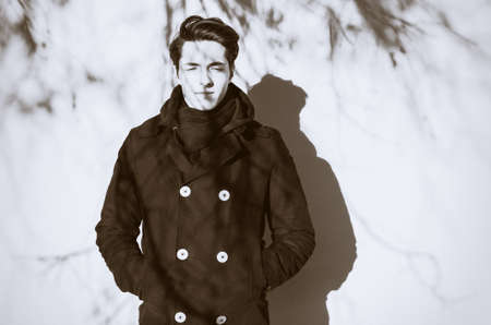 Retro portrait of a thoughtful hipster guy in front of white wall. Black and white retro photo with grainの写真素材