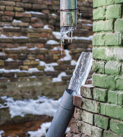 Broken frozen downspout with ice insideの写真素材