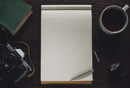 Open notebook, pen, cup of tea, book, retro camera and watch on wooden table, top viewの写真素材