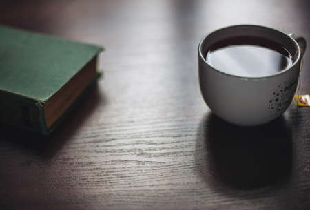 Book and brewing cup of tea on wooden tableの写真素材