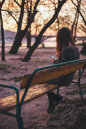 Young woman sitting on the bench using smart phoneの写真素材