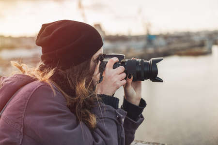 Female photographer taking photos of evening cityの写真素材