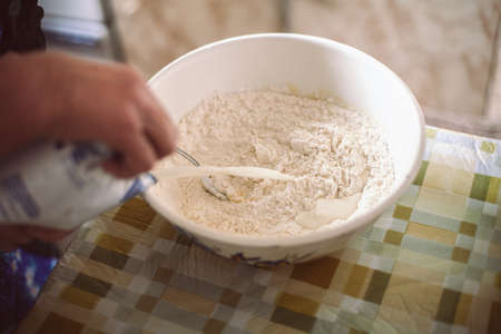 Grandmother pouring milk into pancake batterの写真素材