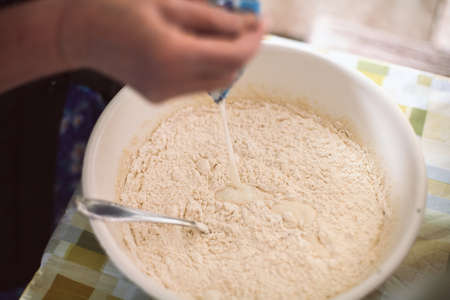 Grandmother pouring milk into pancake batterの写真素材