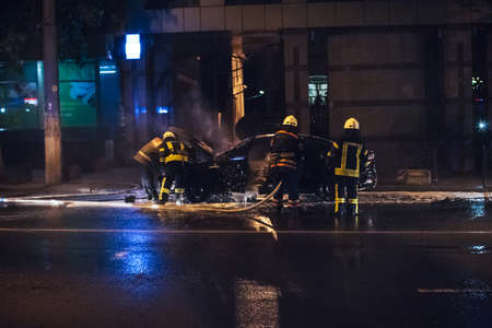 Firemen extinguishing a car fireの写真素材