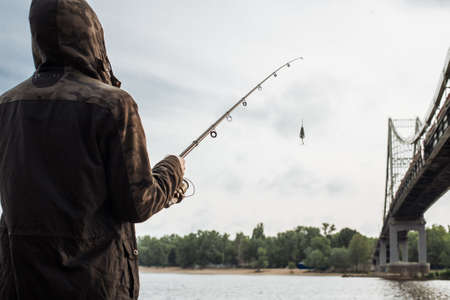 Young man fishing on the river. Fisherman holding spinning rod with spoon baitの写真素材