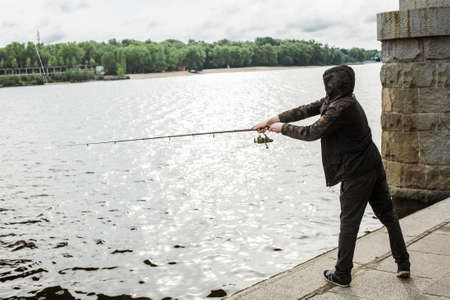 Young man fishing with a spinning on the riverの写真素材