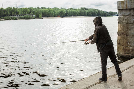 Young man fishing with a spinning on the riverの写真素材