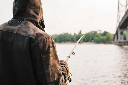 Young man fishing with a spinning on the riverの写真素材