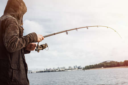 Young man fishing with a spinning on the riverの写真素材