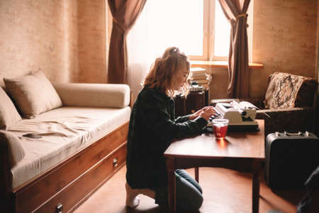 Young female writer using typewriter at homeの写真素材