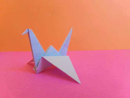 A paper crane on a pink and organge background.の写真素材