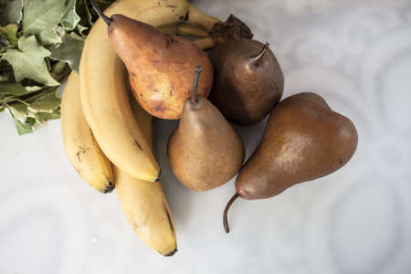 Pears and bananas with ivy leaves over white backgroundの写真素材