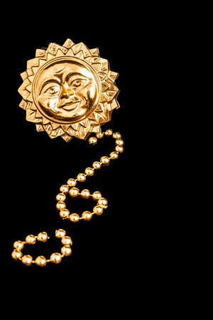 Background or texture with a gold sun in relief and a string of fake gold pearls