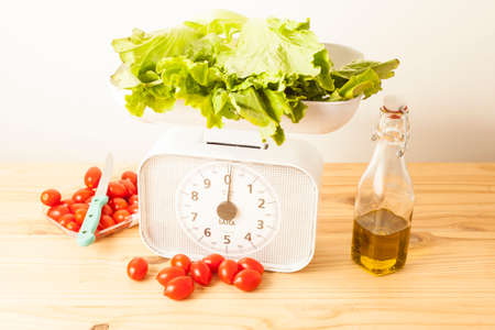 Head of lettuce on a white balance with cherry tomatoes and olive oilの写真素材